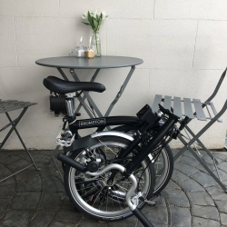 Brompton 2017 M3L Black folded next to cafe table